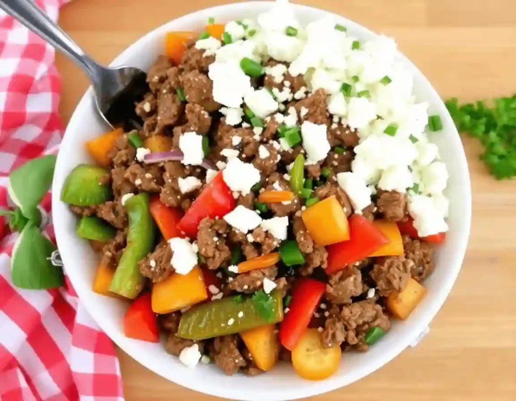 "Sizzling Mediterranean ground beef stir-fry with bell peppers, zucchini, and feta cheese in a skillet. Fresh herbs and vibrant veggies on a rustic background."
